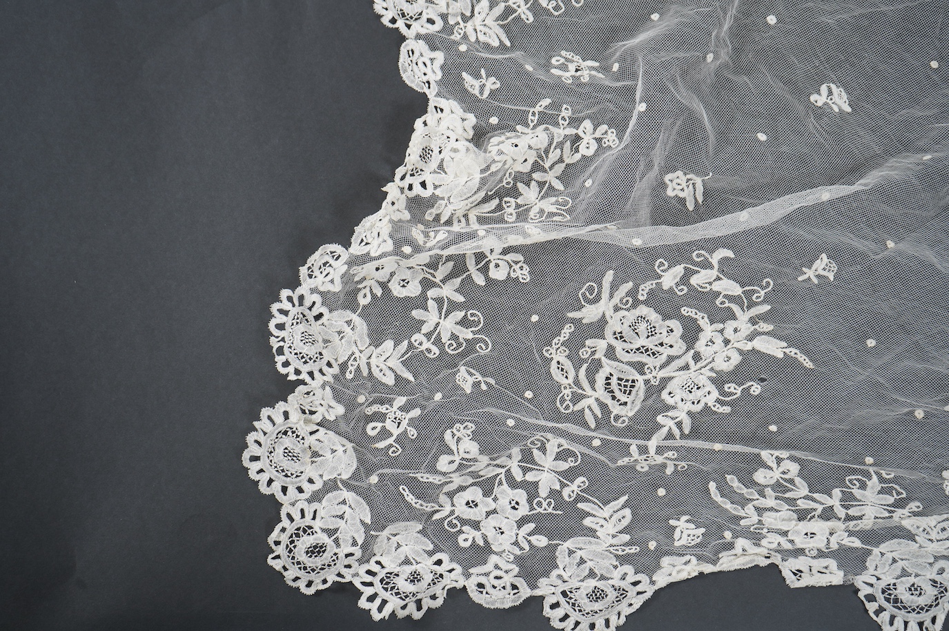 A late Edwardian hand bobbin lace Honiton and net wedding veil, approximately 248cm x 230cm. Condition - one corner has corner has been attached to a hair comb and damaged the netting.